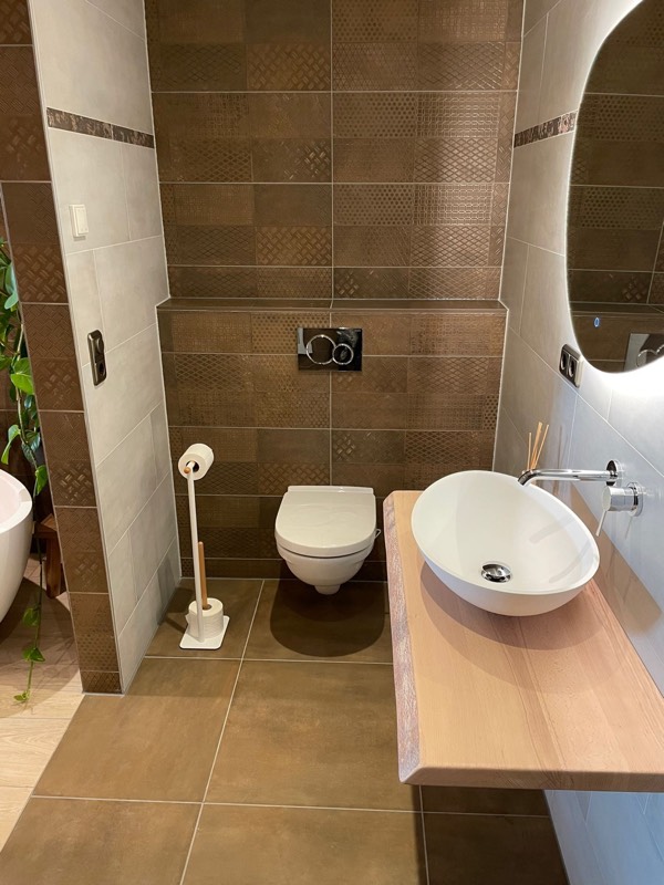 Toilet met bruine decortegels, hangend toilet en zwevend houten wastafelblad